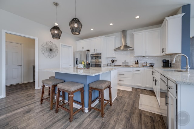 kitchen featuring a sink, white cabinetry, stainless steel appliances, wall chimney exhaust hood, and decorative backsplash