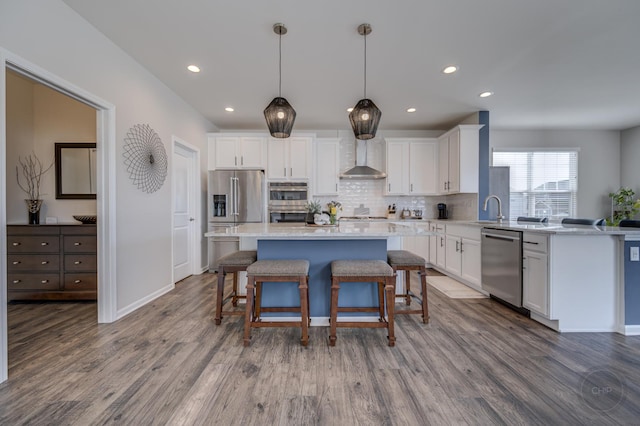 kitchen with white cabinetry, wall chimney exhaust hood, and appliances with stainless steel finishes