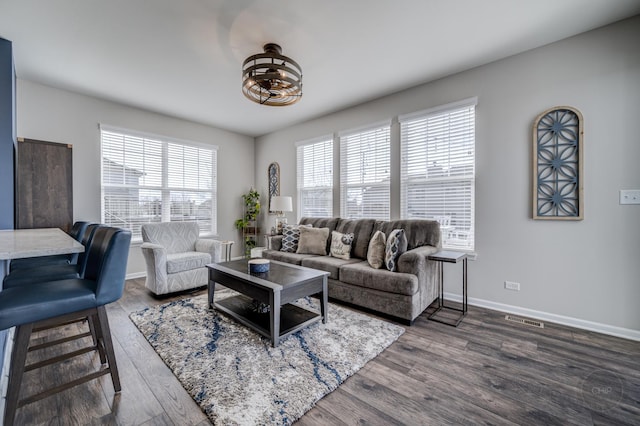 living room with visible vents, baseboards, and wood finished floors