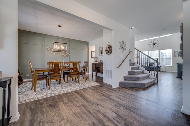 dining area with baseboards, visible vents, stairs, dark wood-type flooring, and a notable chandelier