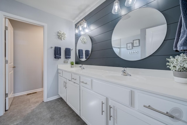 bathroom featuring a sink, visible vents, baseboards, and double vanity