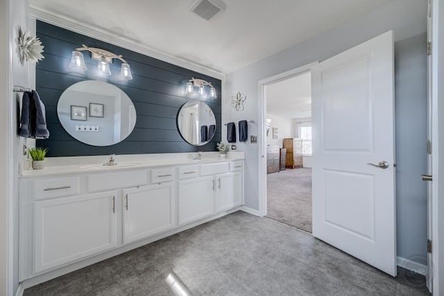 bathroom featuring double vanity, visible vents, baseboards, and a sink