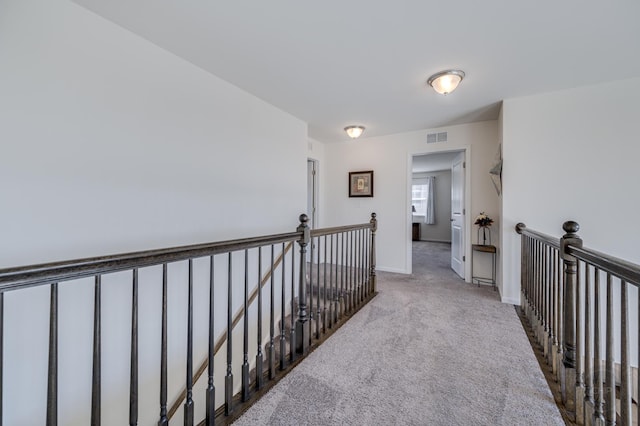 corridor featuring an upstairs landing, visible vents, baseboards, and carpet