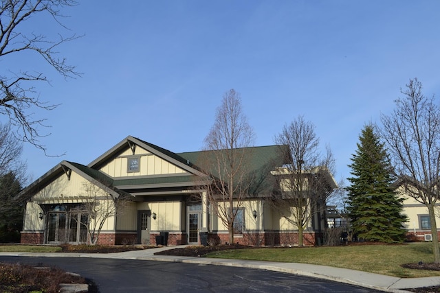 view of front facade featuring brick siding, board and batten siding, and a front lawn