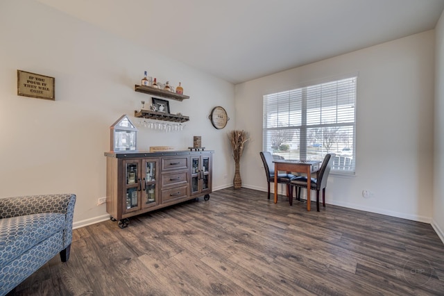 sitting room with a dry bar, dark wood-type flooring, and baseboards