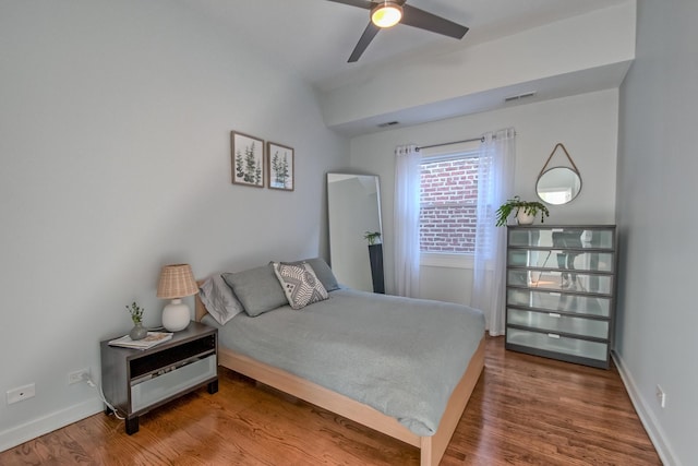 bedroom with ceiling fan, visible vents, baseboards, and wood finished floors