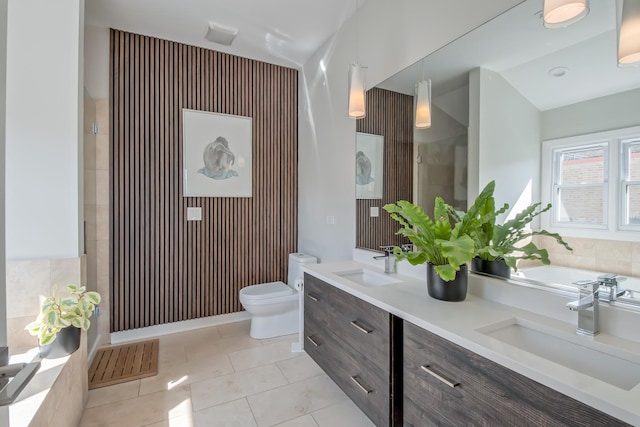 bathroom with tile patterned floors, toilet, double vanity, and a sink