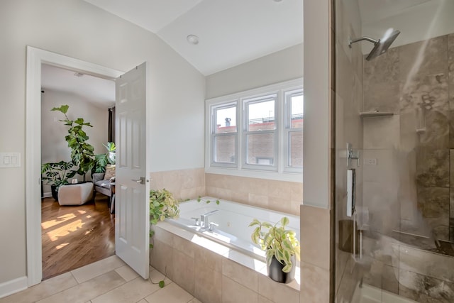 bathroom featuring tile patterned flooring, lofted ceiling, a tub with jets, and a stall shower