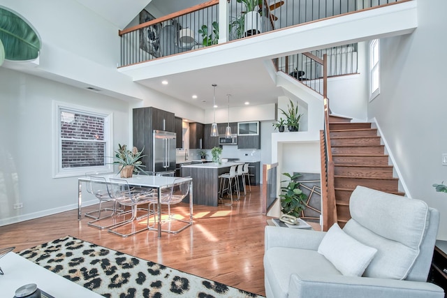 living room with baseboards, a high ceiling, wood finished floors, and stairs