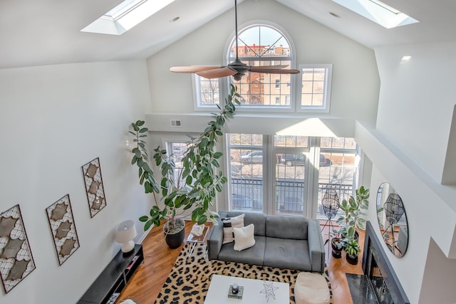 sitting room with visible vents, a skylight, ceiling fan, and wood finished floors