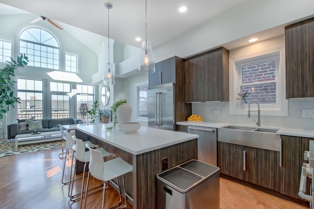 kitchen featuring a kitchen island, a breakfast bar, a sink, stainless steel appliances, and modern cabinets