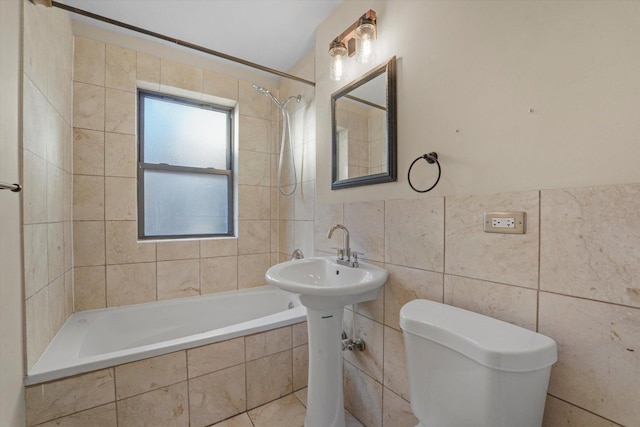 bathroom featuring tile walls, toilet, and tiled shower / bath