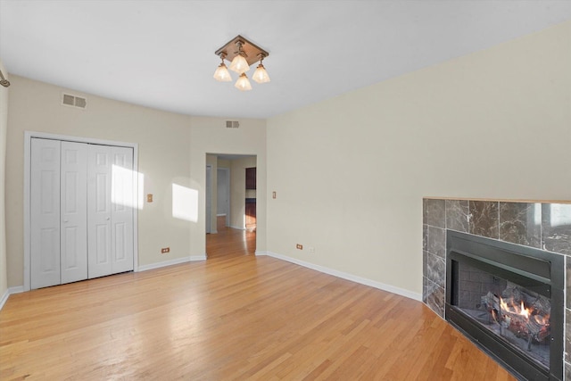 unfurnished living room featuring visible vents, baseboards, a fireplace, and light wood finished floors