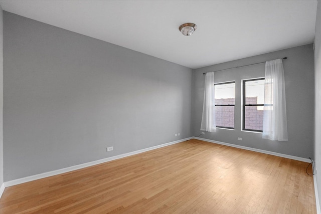 spare room with baseboards and light wood-type flooring