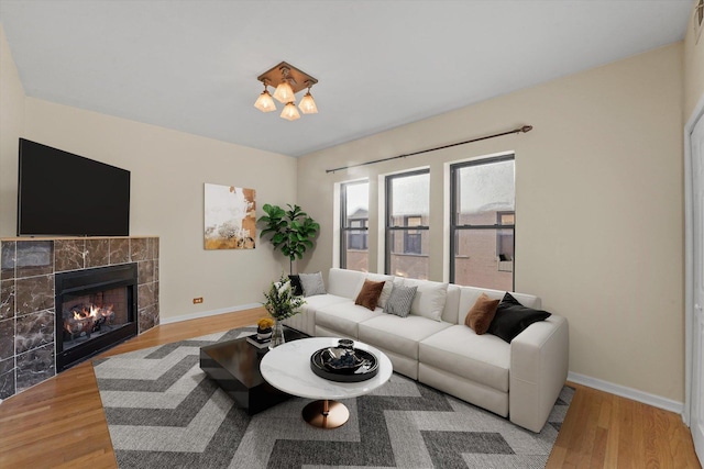 living area featuring wood finished floors, baseboards, and a tile fireplace