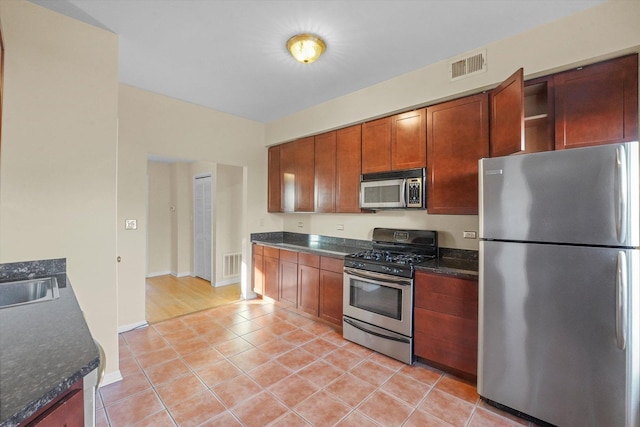 kitchen with a sink, light tile patterned floors, visible vents, and stainless steel appliances