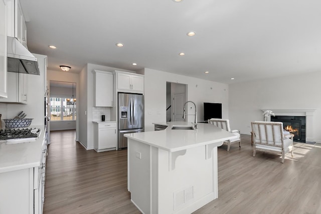 kitchen featuring a sink, open floor plan, light wood-style floors, stainless steel fridge with ice dispenser, and light countertops