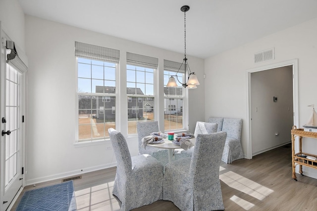 dining space with light wood-type flooring, visible vents, and an inviting chandelier