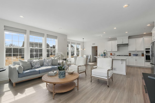 living room featuring recessed lighting, a notable chandelier, and light wood finished floors