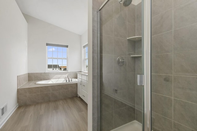 bathroom featuring vanity, wood finished floors, lofted ceiling, a shower stall, and a bath