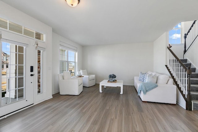 living room featuring stairway, baseboards, and wood finished floors