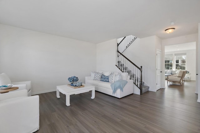 living room featuring baseboards, wood finished floors, and stairs