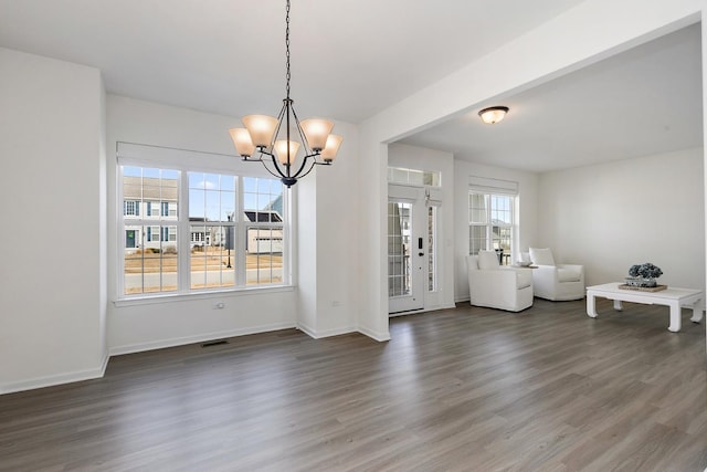 unfurnished dining area with visible vents, baseboards, an inviting chandelier, and wood finished floors