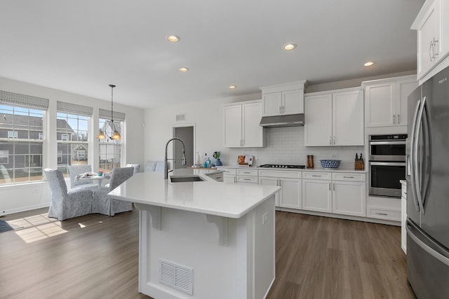 kitchen featuring visible vents, under cabinet range hood, appliances with stainless steel finishes, dark wood-style floors, and a sink