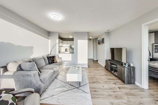 living area with light wood-type flooring and baseboards