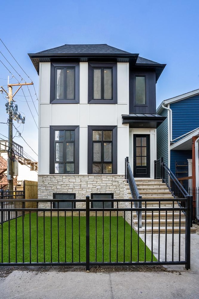 view of front of house featuring a front lawn, stone siding, a fenced front yard, and stucco siding