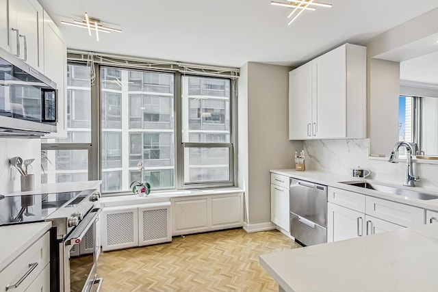 kitchen featuring radiator heating unit, stainless steel appliances, a sink, light countertops, and white cabinets