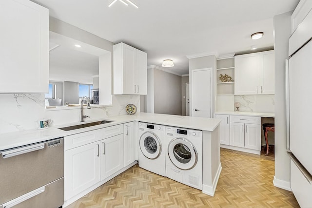 clothes washing area featuring ornamental molding, separate washer and dryer, and a sink