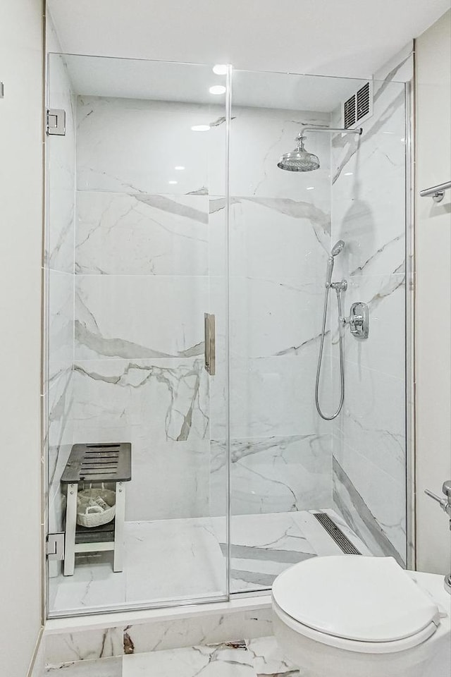 bathroom featuring toilet, visible vents, marble finish floor, and a marble finish shower