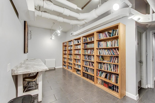 interior space with radiator heating unit, wall of books, and baseboards