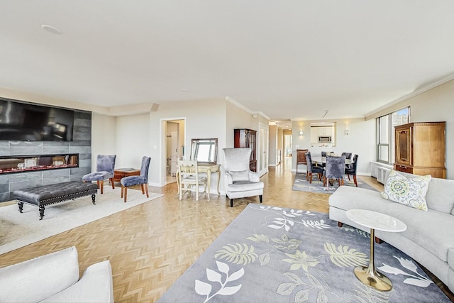 living area with plenty of natural light, crown molding, baseboards, and a glass covered fireplace