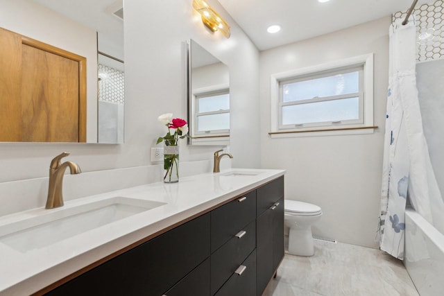 full bathroom featuring double vanity, toilet, visible vents, and a sink