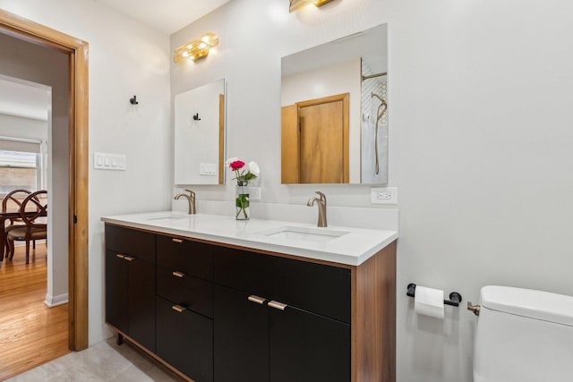 full bath featuring a sink, toilet, wood finished floors, and double vanity