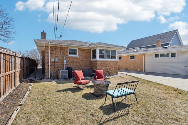 rear view of property featuring fence, cooling unit, a fire pit, brick siding, and a chimney