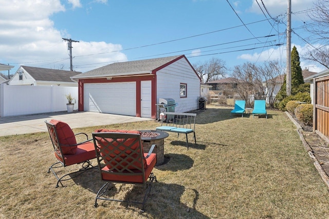 view of yard featuring an outbuilding, a fire pit, a detached garage, and fence