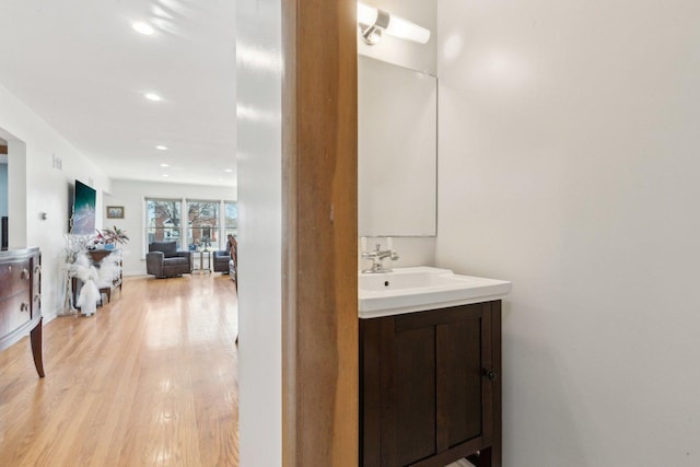 bathroom with recessed lighting, wood finished floors, and vanity