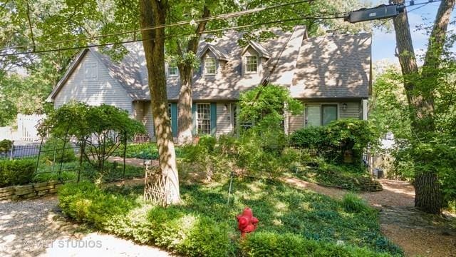 cape cod house featuring fence