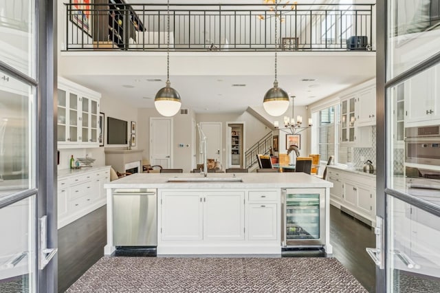 kitchen with wine cooler, white cabinets, glass insert cabinets, and a sink