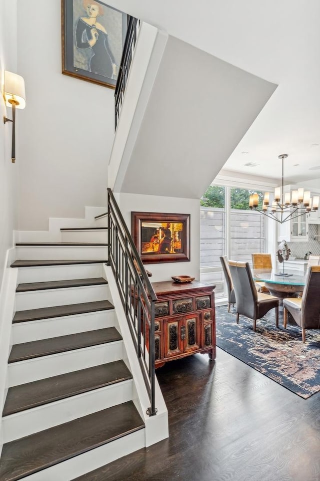 stairs with an inviting chandelier and wood finished floors