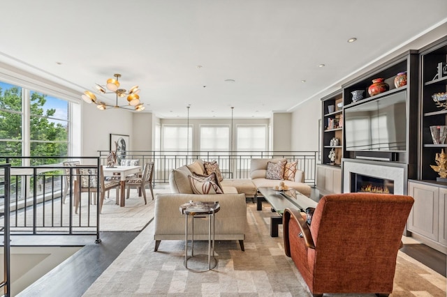 living room featuring wood finished floors, a warm lit fireplace, and a chandelier