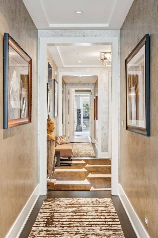 corridor featuring baseboards and dark wood-style flooring