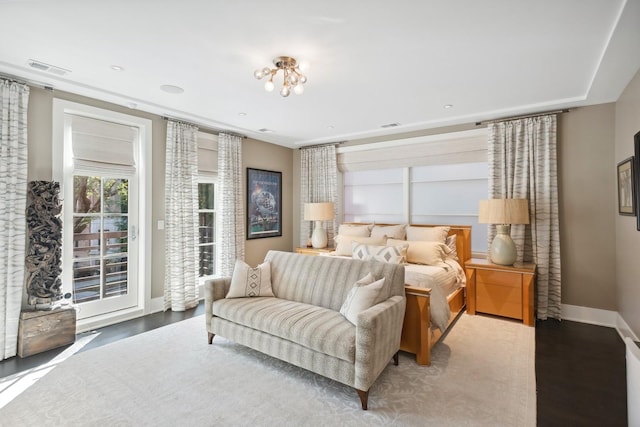 bedroom with access to outside, visible vents, baseboards, and wood finished floors