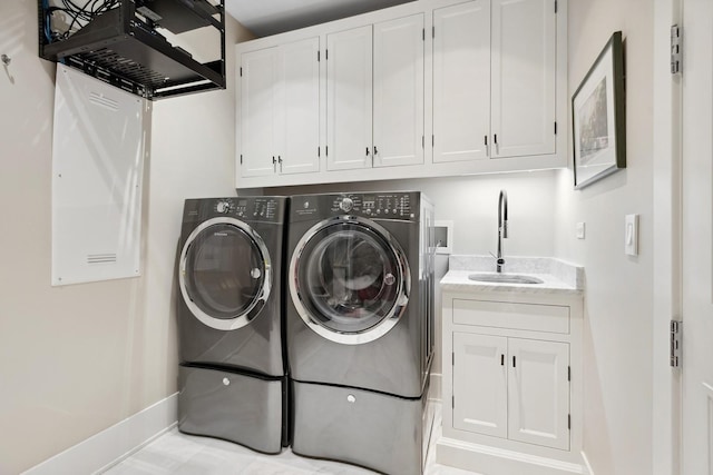 laundry area featuring washer and dryer, cabinet space, baseboards, and a sink