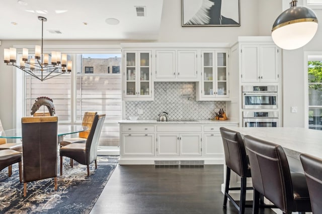 kitchen featuring visible vents, backsplash, double oven, light countertops, and a sink