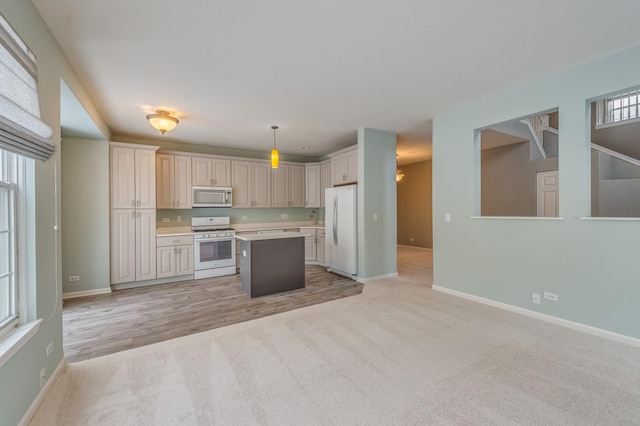 kitchen featuring white appliances, baseboards, light countertops, light colored carpet, and a center island