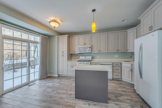 kitchen with white appliances, visible vents, light wood-style flooring, a sink, and light countertops